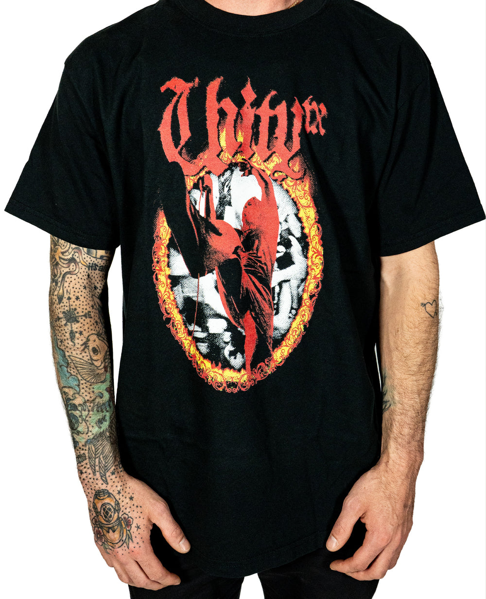 A person in a black UNITYTX Comfort Colors tee with "Unity" in red gothic letters above a fiery ring and red figure stands against a plain white background, showing tattooed arms.