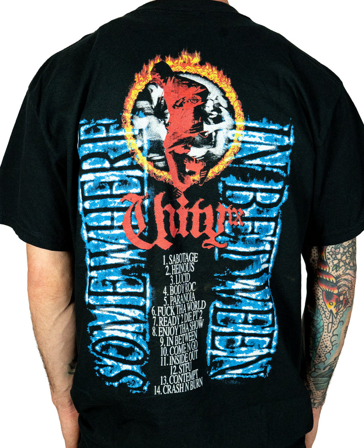 Someone wears a black UNITYTX Comfort Colors tee with a fiery clown face and red “Unity” on the front, 14 song titles on the back, and blue distorted “Somewhere In Between” text vertically along both sides.