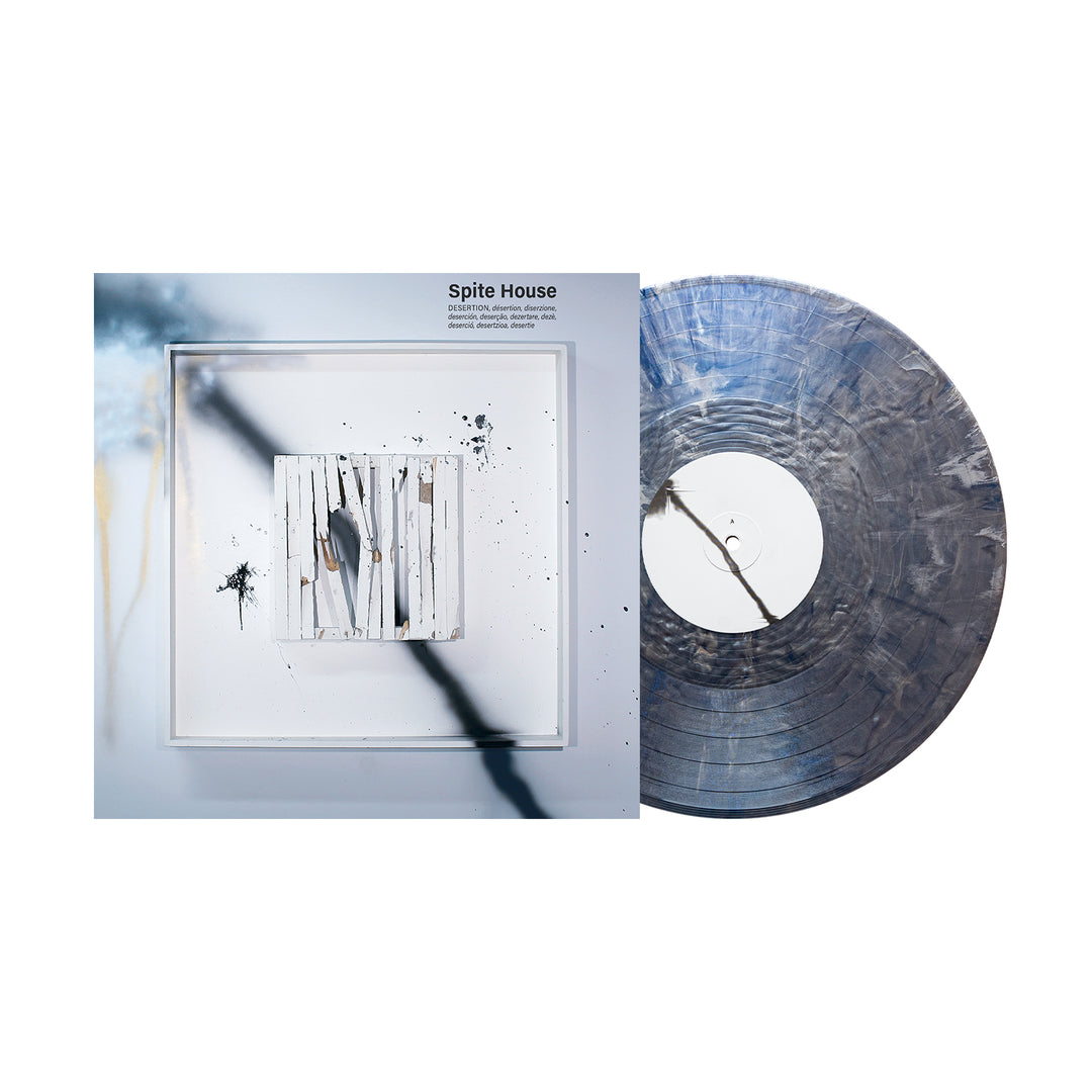 A limited edition Spite House vinyl with a gray and white marbled pattern rests beside its album cover, showcasing abstract art of white slats, paint splatters, and blurred shadows.