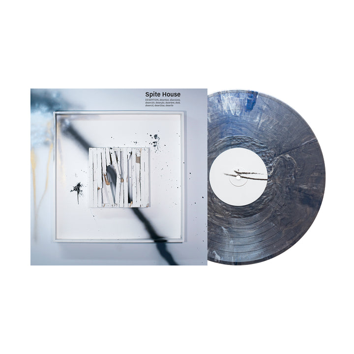 A Spite House "Desertion" vinyl LP in smoky gray and white marbled pattern sits beside its album cover, which displays abstract art with white vertical slats, black paint splatters, and blurred shadows on a light background.