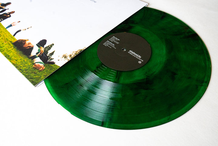 A Stateside Green Smoke Vinyl record partially slides out of its sleeve, which features a photo of people lying on grass under a blue sky.