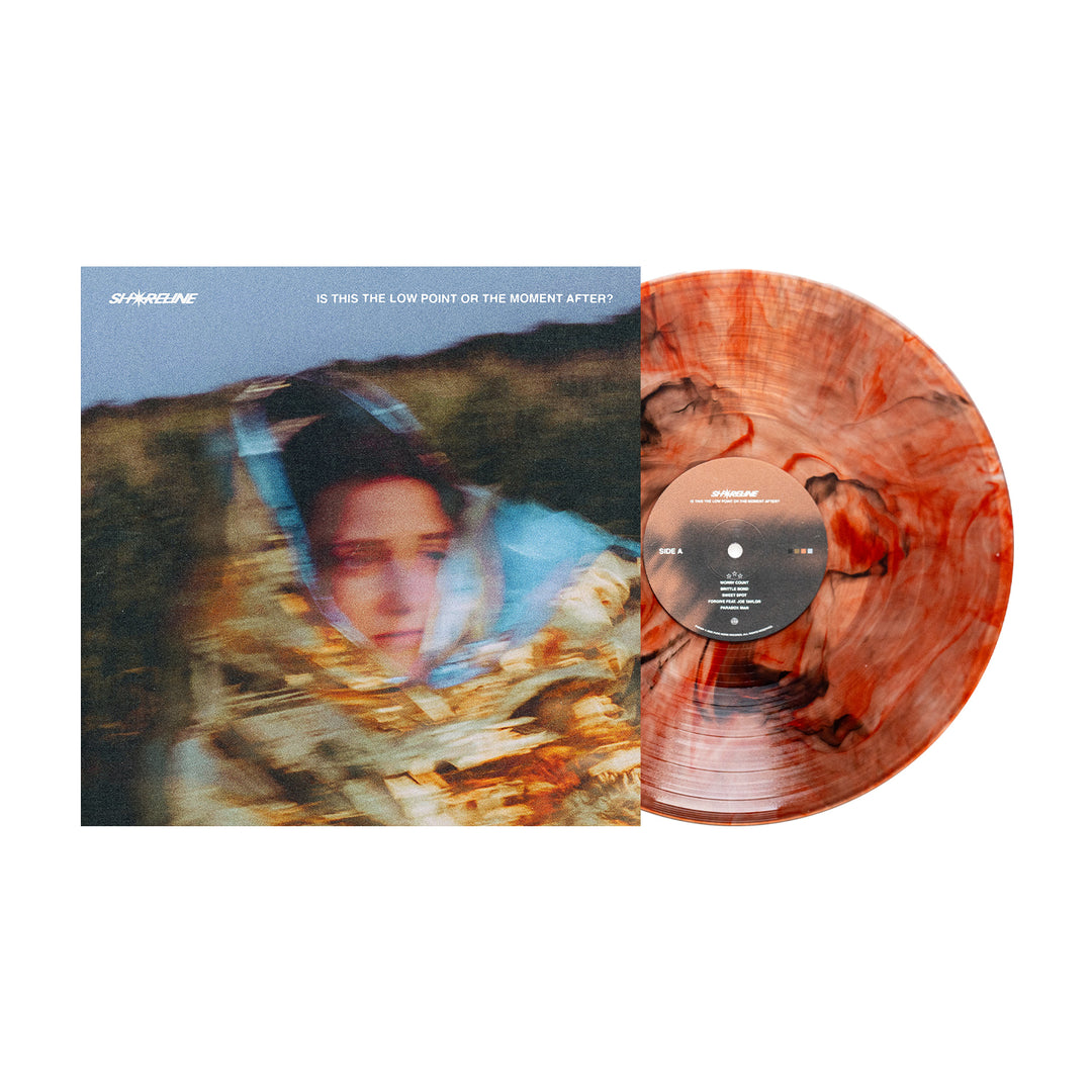 A Shoreline Amber Deluxe Marble Vinyl LP sits beside its cover, showing a blurry figure in a shiny blanket, with the album title "is this the low point or the moment after?" Vinyl LP presale available now.
