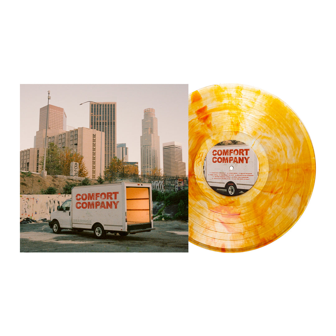 A yellow Bearings Citrine Deluxe Marble Vinyl LP lies by its album cover, which shows a moving truck with the band's logo in front of city buildings at sunset—an eye-catching vinyl available now for album presale.