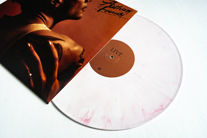 A white and pale pink Guava Cream Vinyl record by Anthony Family, partially pulled from its cover featuring a persons back and arm with stylized text LIV.E, Primary, and Live From An Ordinary Place—ideal for presale collectors.