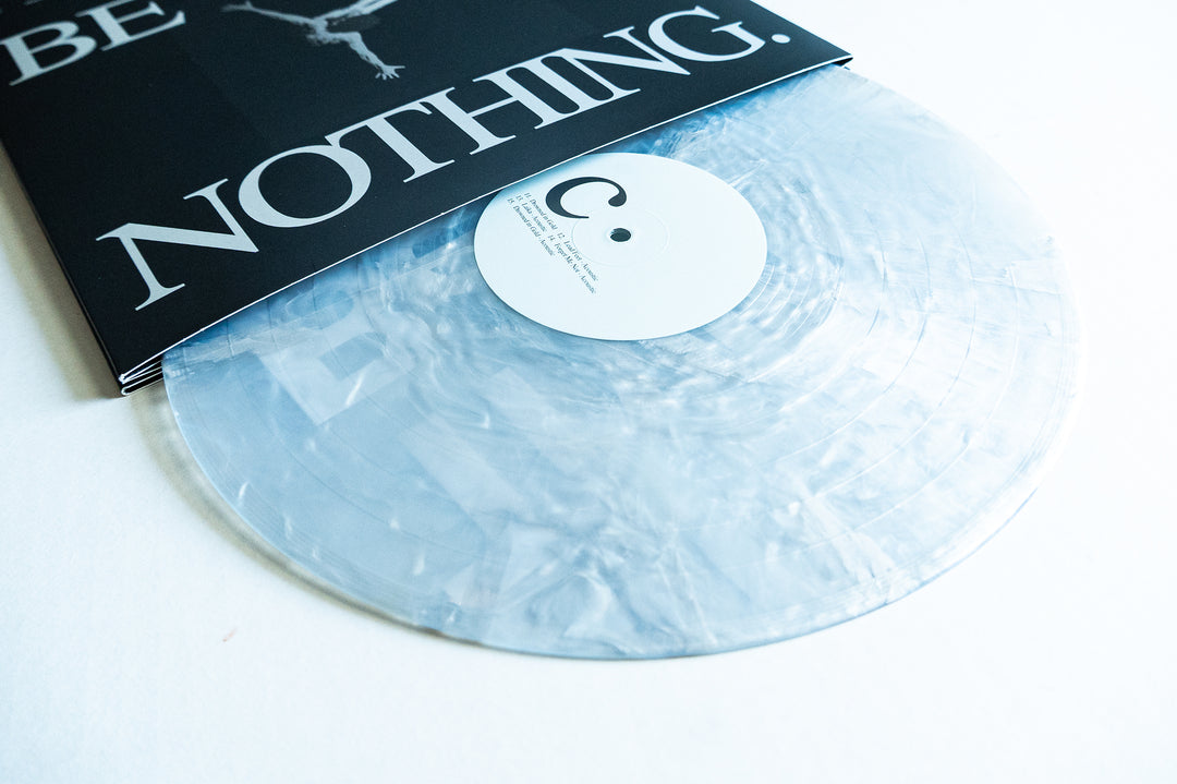 A translucent, marbled vinyl record from Boston Manor’s Be Nothing album partially slides out from a black and white sleeve featuring bold “NOTHING” text. The white label with minimal black text and a small circle complements Boston Manor’s distinct Be Nothing aesthetic.