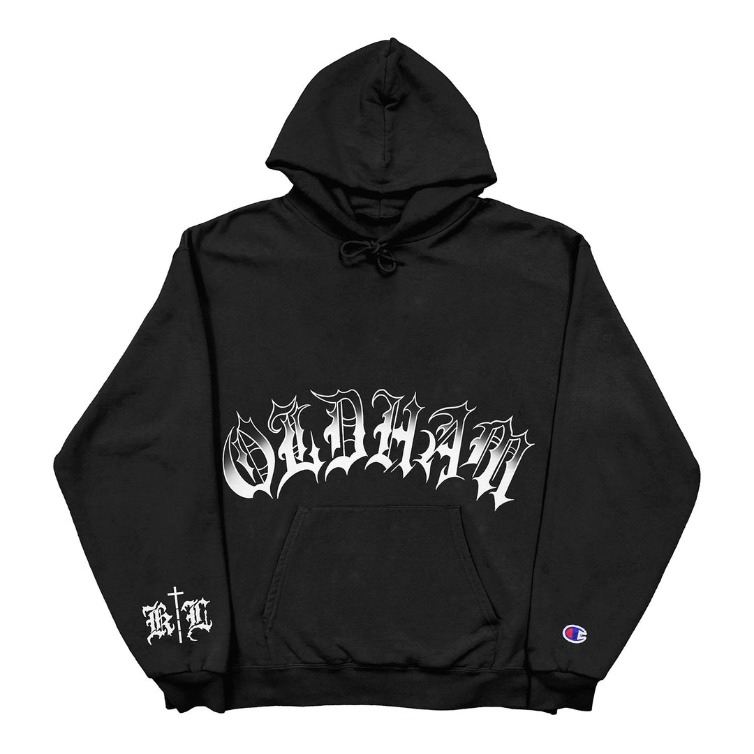 Black hoodie by Knocked Loose featuring large, ornate white gothic "Oldham" text on the chest, small gothic print on the left wrist, and a Champion logo on the left sleeve cuff—ideal for fans of printed Champion pullovers.