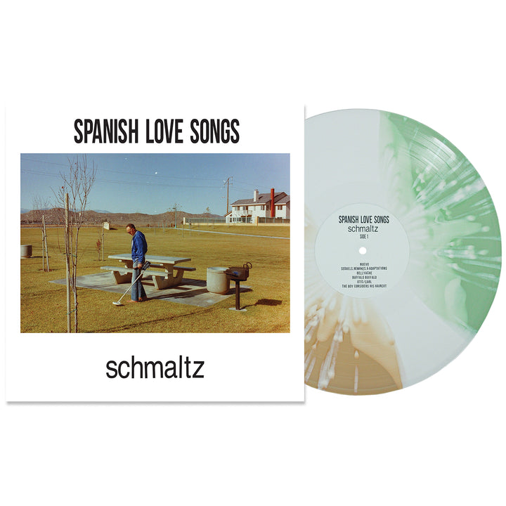 Spanish Love Songs "Schmaltz" vinyl record features a white and green swirl with white splatter. The cover shows a person by a picnic table, beer bottles, houses, and trees in the background.