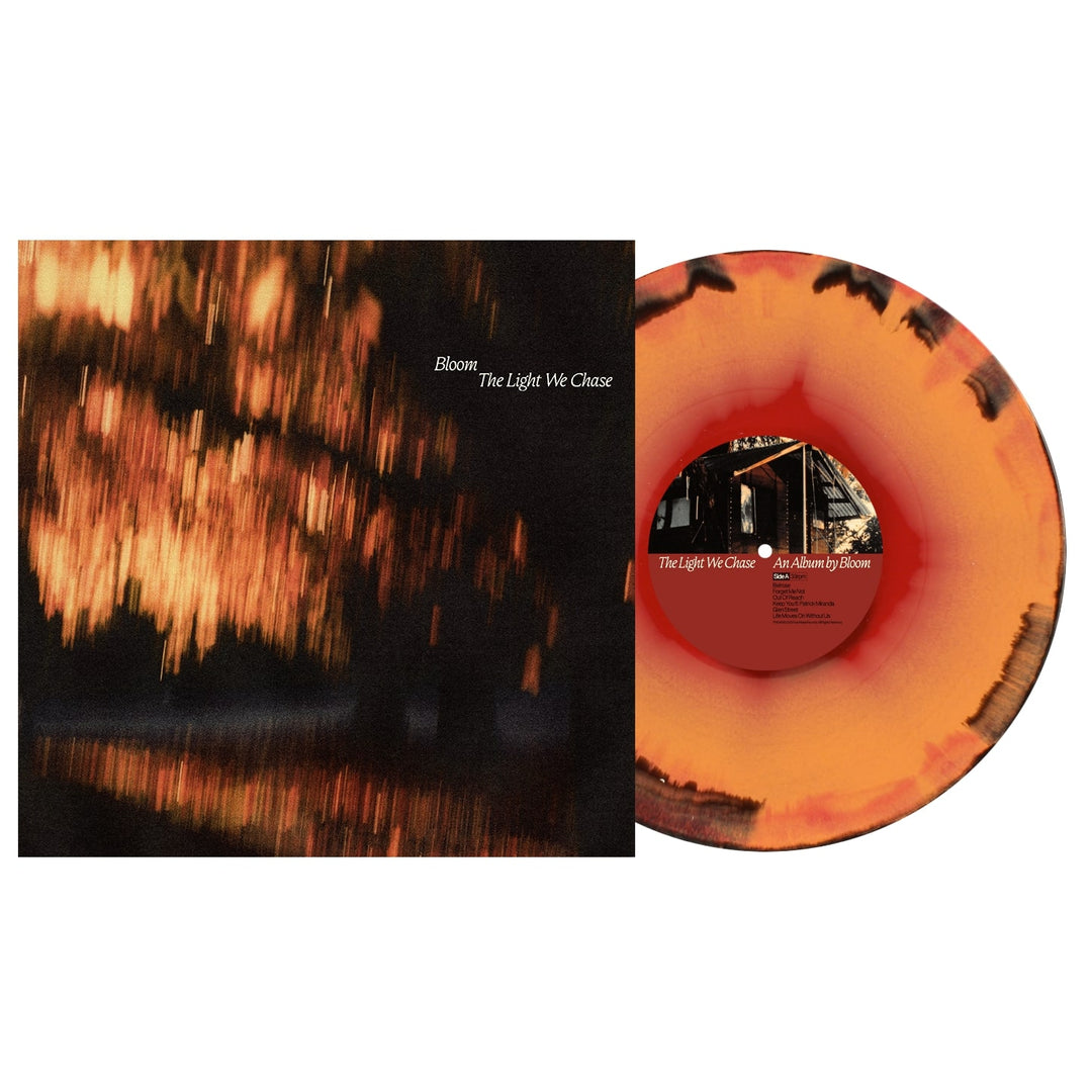 A Bloom colored vinyl LP with an orange and black swirl pattern is shown beside its album cover, which features a blurred image of glowing lights and the title The Light We Chase in small white letters.