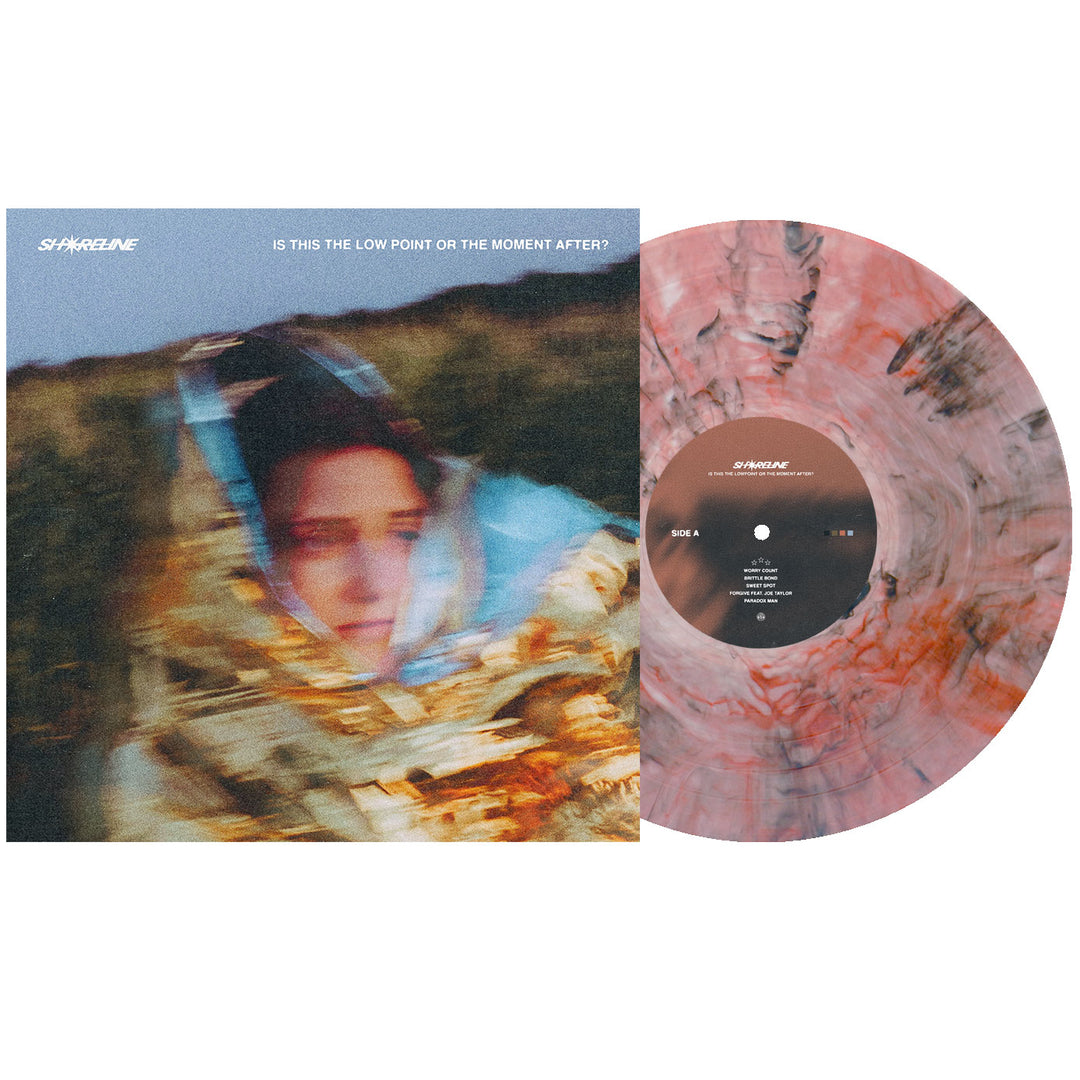 A marbled pink and gray Shoreline Amber Deluxe Marble Vinyl LP sits by its cover—featuring a person in a shiny blanket, blurred on grass. The presale LP reads: Is This the Low Point or the Moment After?.