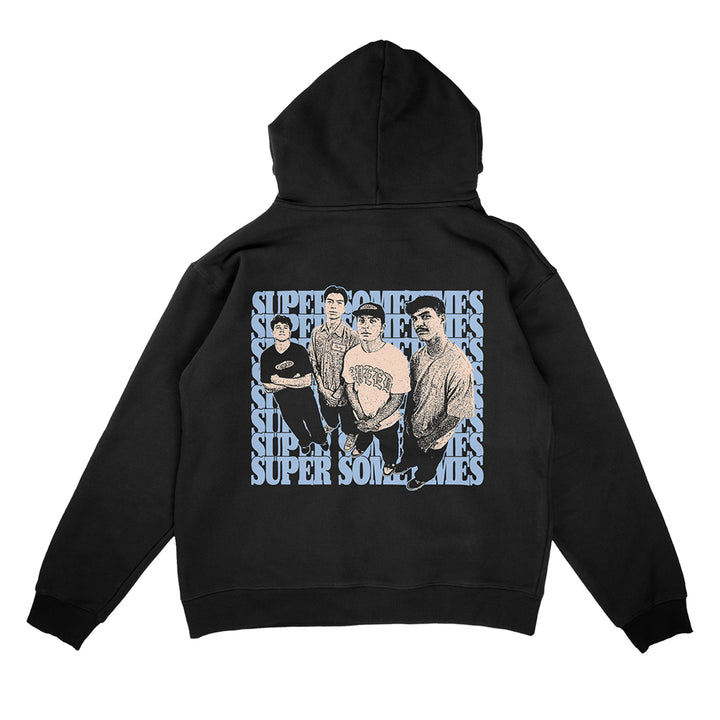 A Super Sometimes black hooded sweatshirt featuring an illustration of four people standing together, with the word SUPERSOMETHING repeated in bold, overlapping blue and white font behind them.