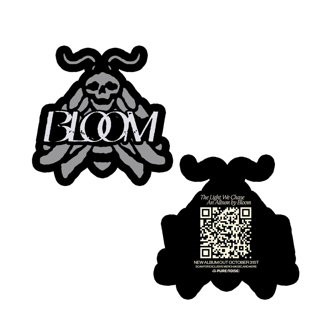 Set of two black and grey moth-shaped stickers by Bloom. Front features BLOOM with a skull and wings; back displays a QR code, album release info, and The Light We Chase, capturing mysterious novel-like intrigue.