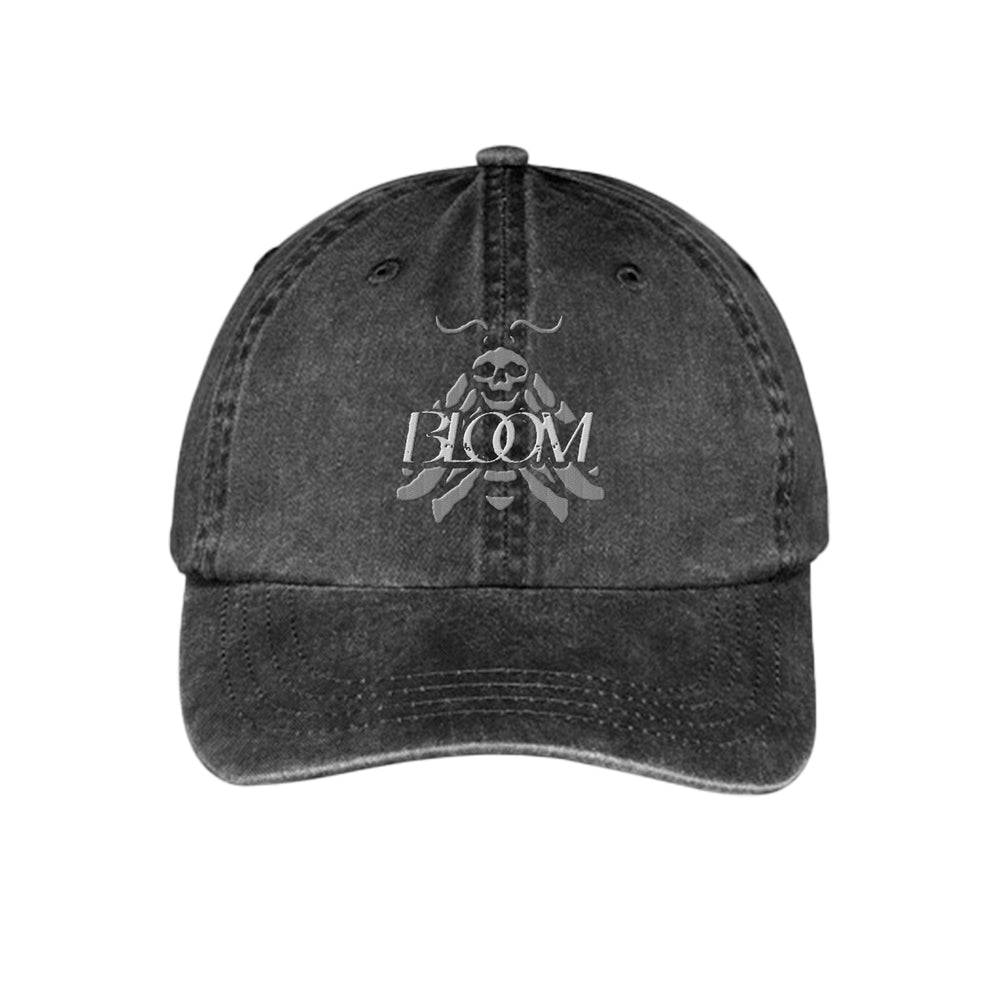 A vintage black denim dad hat by Bloom featuring a white skull, crossed swords, and the word BLOOM printed on the front.