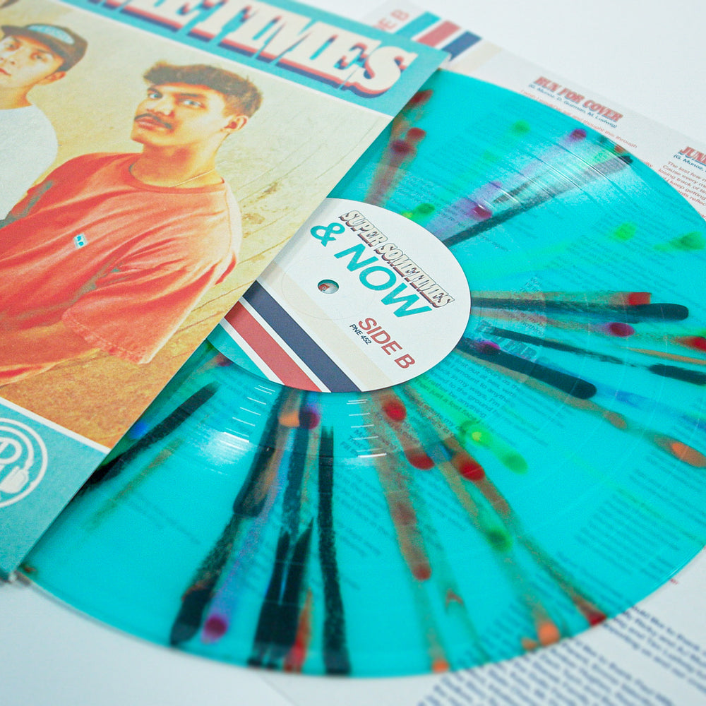 A turquoise vinyl with Rainbow Splatter from Super Sometimes sits partially in its sleeve, which displays a photo of two men and bold "Then & Now" text. The record label shows it’s Side B.