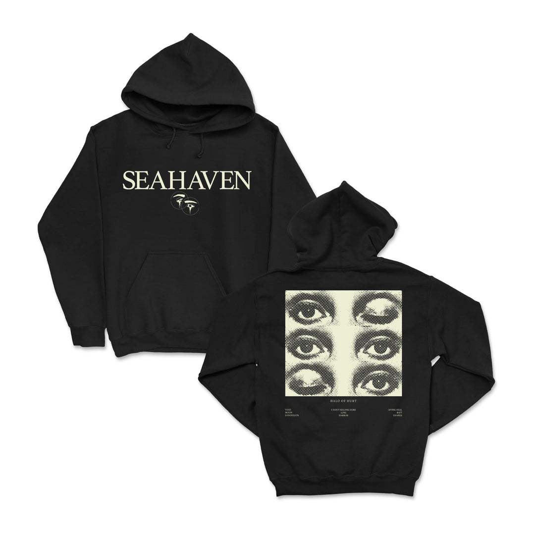 A black midweight Seahaven pullover hoodie featuring "SEAHAVEN" and a small face graphic on the front. The back displays a large design with six illustrated eyes in three rows and small text at the bottom.