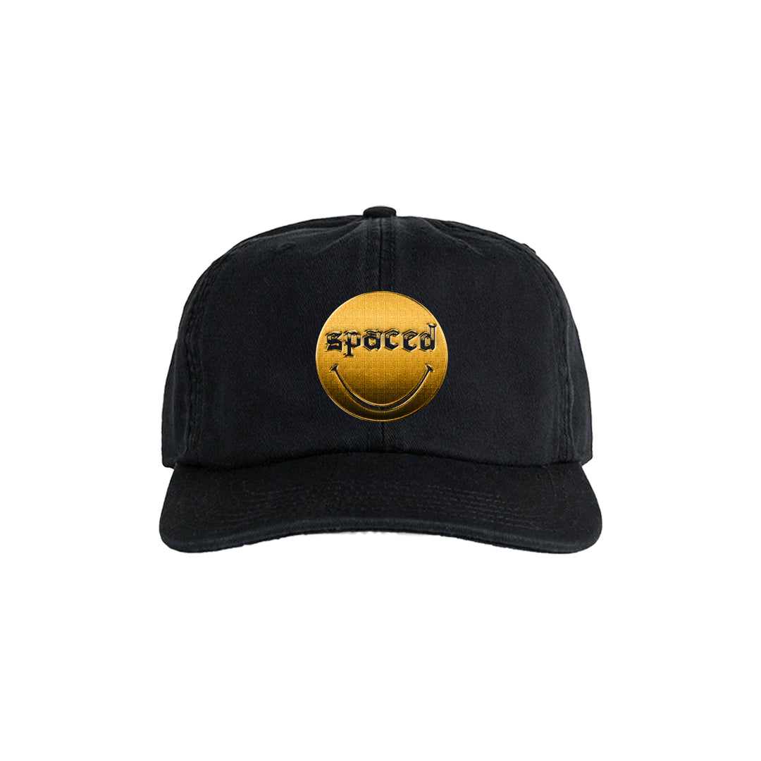 The Spaced black dad hat features a gold circular patch with a smiley face and spaced written above it in a unique font.