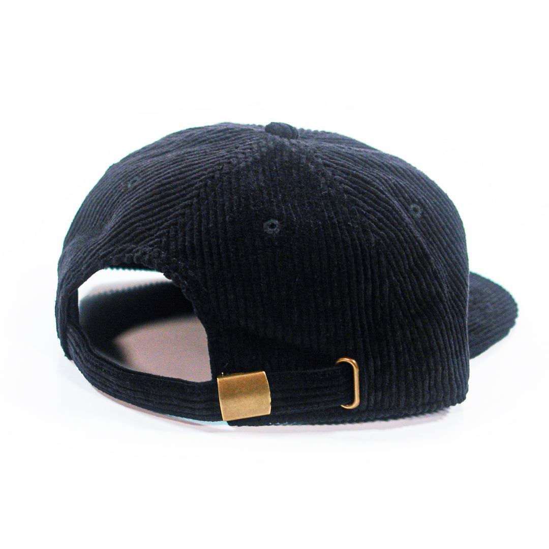 back of a black corduroy cap with a gold buckle on a white background