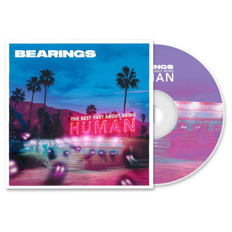 Bearings The Best Part About Being Human CD. Album art depicts a diner with a mountain and palm trees in the background. spooky looking lights seem to be entering the diner. CD is exposed to show art on disc. art on disc is same as the album cover.