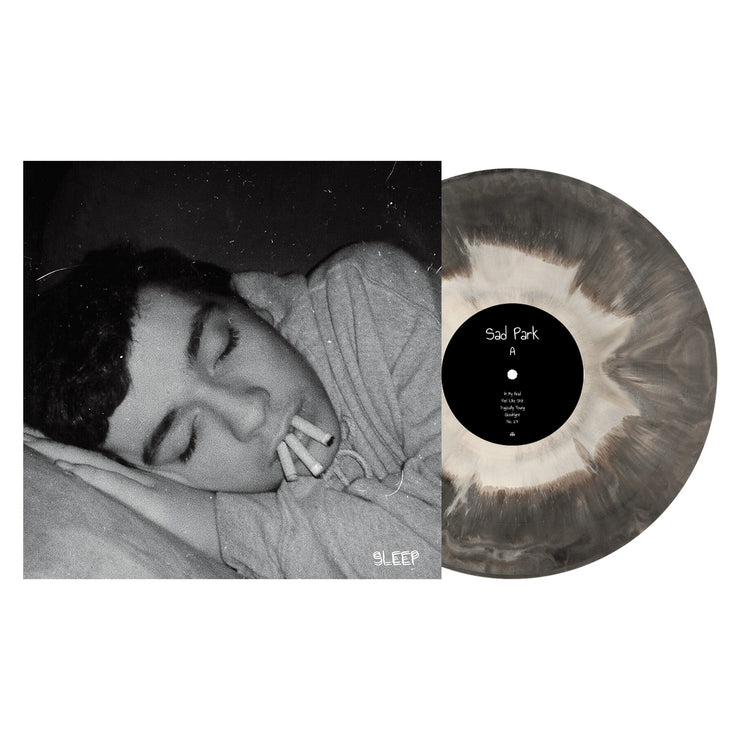 Side A of Sad Parks "Sleep" Vinyl LP with vinyl exposed to show color. color of vinyl is Black and White galaxy mix. Album Art is a man asleep with 3 cigarettes in his mouth. 