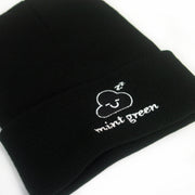 angled, close up image of a black cuffed winter beanie on a white background. front, center part of the cuff has white embroidery of a cloud face with two Z's at the top, and says mint green below