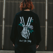 image of the back of a woman wearing a black crewneck sweatshirt. two skeleton hands, holding hands with 3 pink roses wrapped around them with the text Dont Die Today under it on the back.