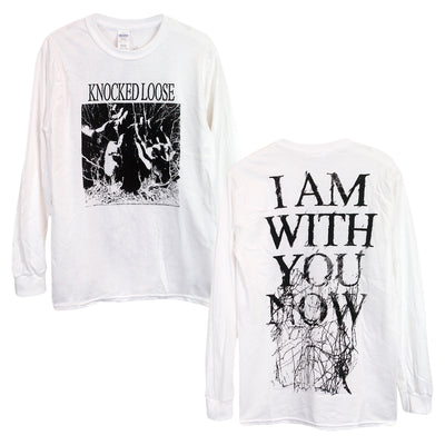 image of the front and back of a white long sleeve tee shirt on a white background. front of the long sleeve is on the left and has a full chest print in black. Knocked loose is written at the top and below that is an image of a persons face with sunglasses on and hands up with white scribbles surrounding it. The back of the long sleeve is on the right and has a full back print in black that says i am with you now and has black scribbles.