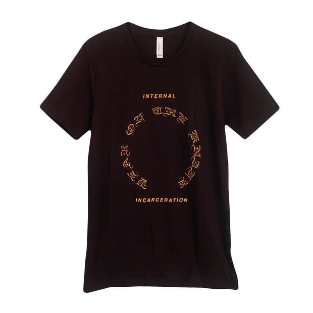 image of the front of an oxblood black tee shirt on a white background. front of the tee has a full chest print in yellow. in the center it says year of the knife in a circle. above says internal, and below says incareration.