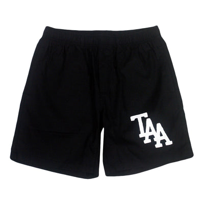 image of black beach shorts on a white background. small print in white on the right thigh of the letters T A A. 