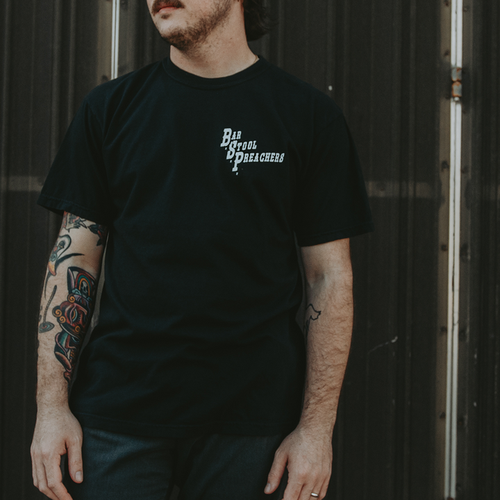 image of a man wearing a black tee shirt. black tee with "Bar Stool Preachers" printed in white on the front left chest.