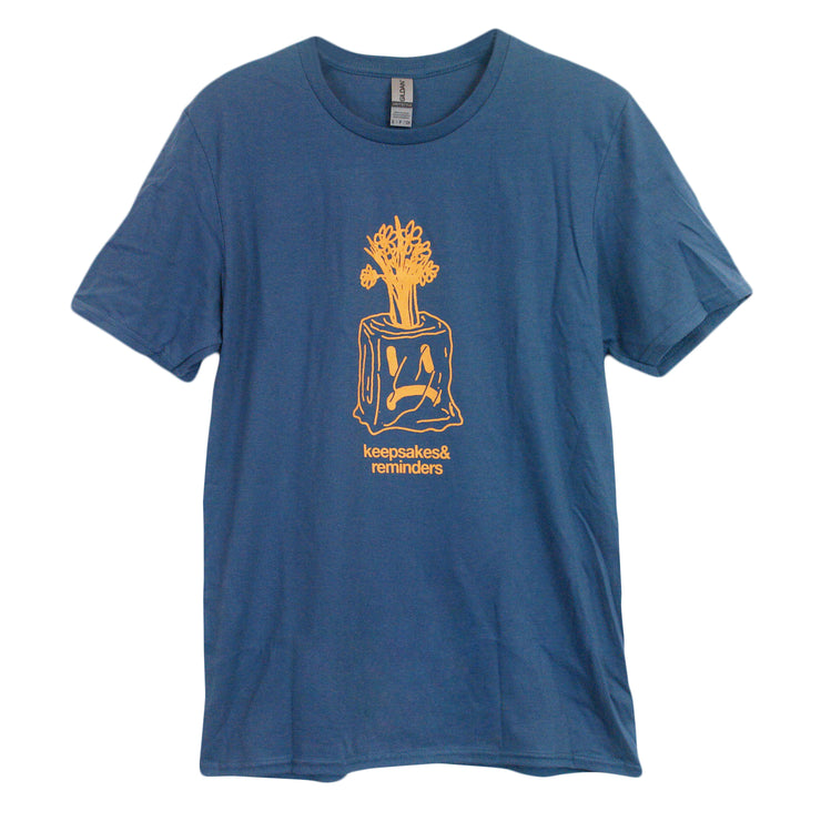 image of an indigo tee shirt on a white background. there is a front and center chest print in orange of a tree stump with a sad face n it and scribbled tree on top. below says keepsakes & reminders