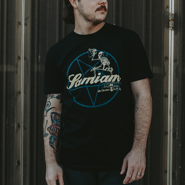 image of a man wearing a black tee shirt.  front of shirt has a pentagram with "Samiam" printed in yellow in the center of pentagram. A skeleton has its foot leaning on the word samiam with a beer glass raised. 