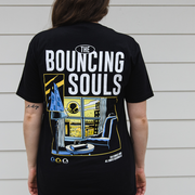 image of that back of a woman wearing a black tee shirt. the back of the shirt is the albums cover art which depicts a person sitting by the window looking out to the city to see the bouncing souls symbol in the sky 